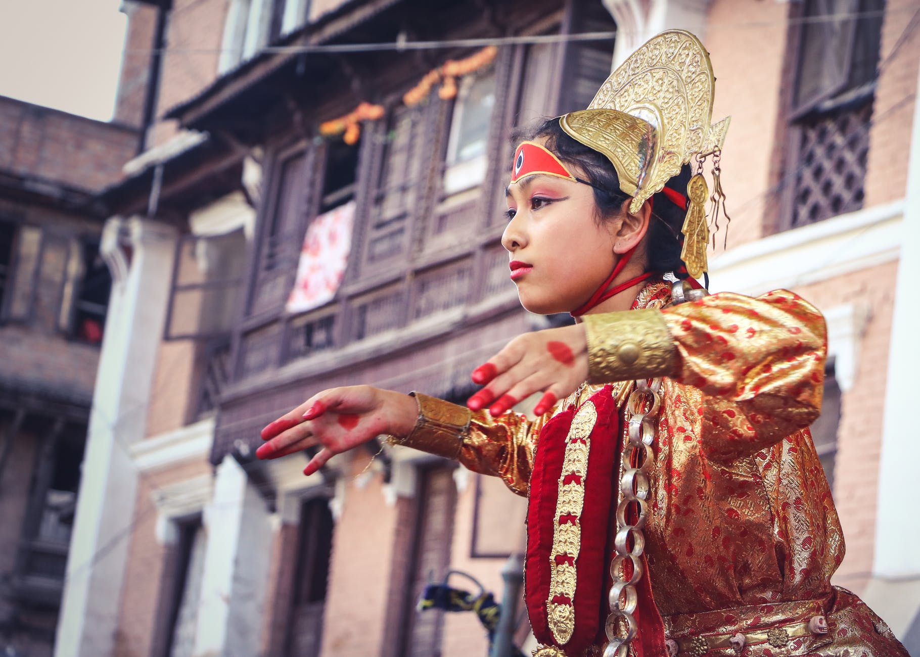 woman wearing yellow and red traditional dress dancing near building